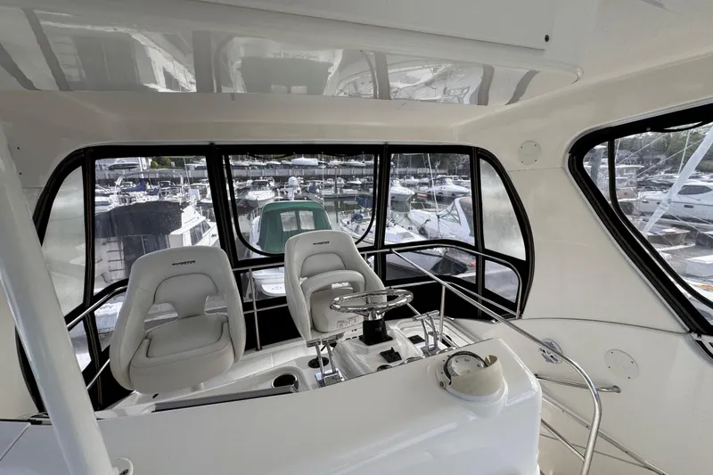 Slide: The Image of Interior view of 2004 Silverton 38 Convertible yacht helm with marina background. - 36
