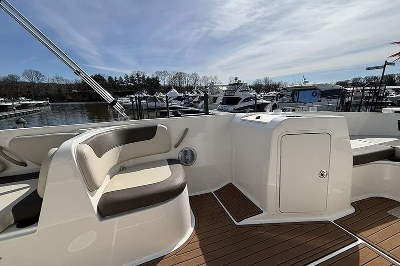 Slide: The Image of 2018 Bayliner Element E21 boat interior with seating and docked boats in background. - 13