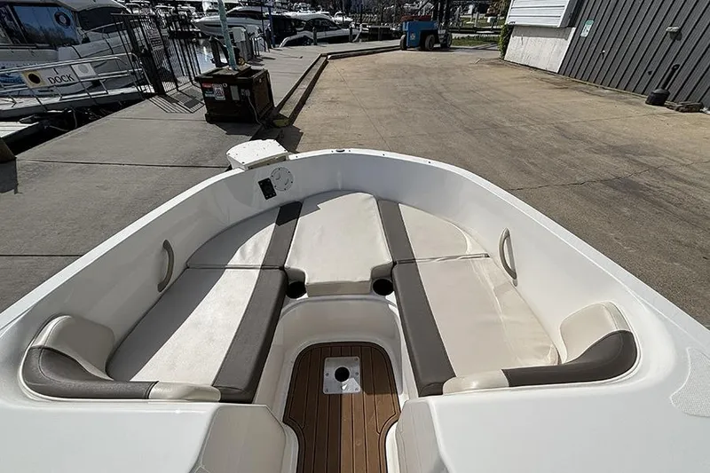 Slide: The Image of 2018 Bayliner Element E21 boat interior with cushioned seating at dockside. - 17