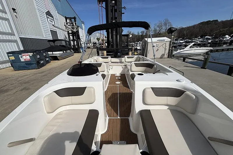 Slide: The Image of 2018 Bayliner Element E21 boat with spacious seating, docked at a marina under clear skies. - 21