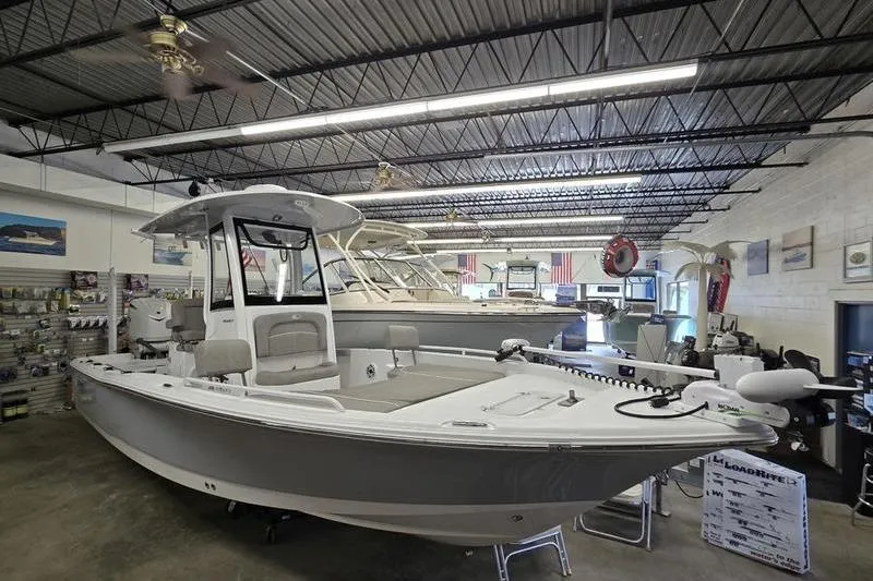 The Image of 2025 Sea Hunt BX 25 FS boat displayed in a showroom with other vessels. - 1