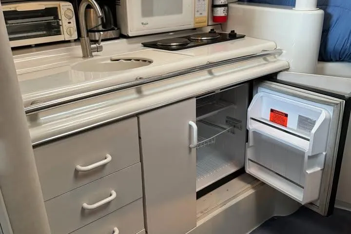 Slide: The Image of 1994 Chris-Craft 322 Crowne yacht kitchenette with sink, stove, and open fridge. - 20