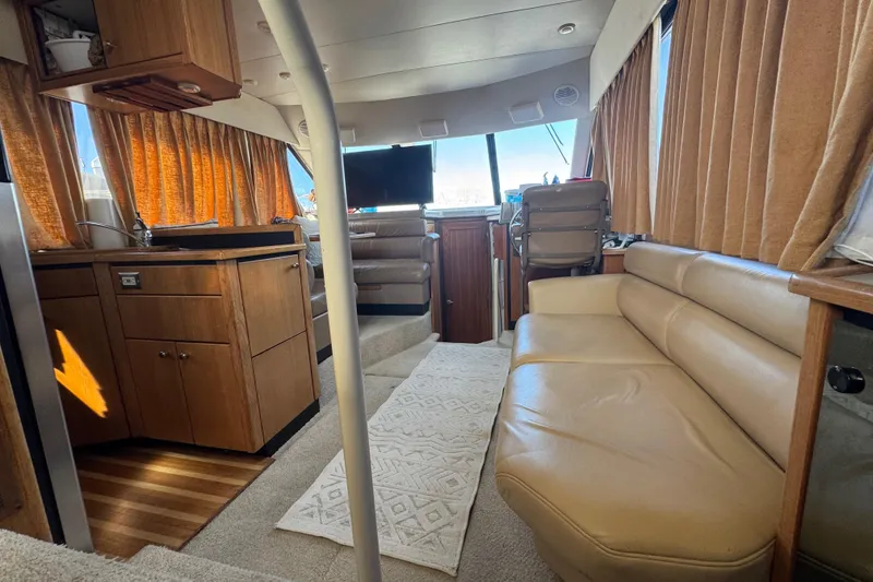 Slide: The Image of 1998 Bayliner 4087 Aft Cabin Motoryacht interior with beige seating, wood cabinetry, and large windows. - 15
