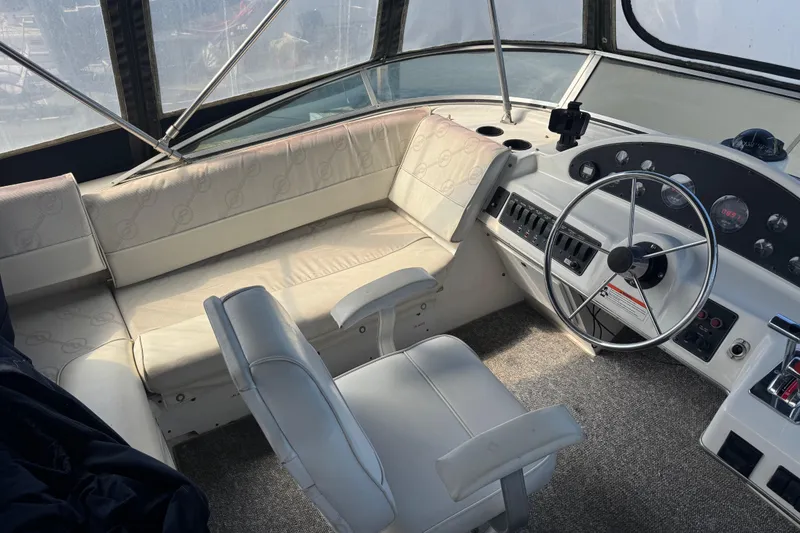 Slide: The Image of 1998 Bayliner 4087 Aft Cabin Motoryacht helm with white seating and steering wheel. - 4