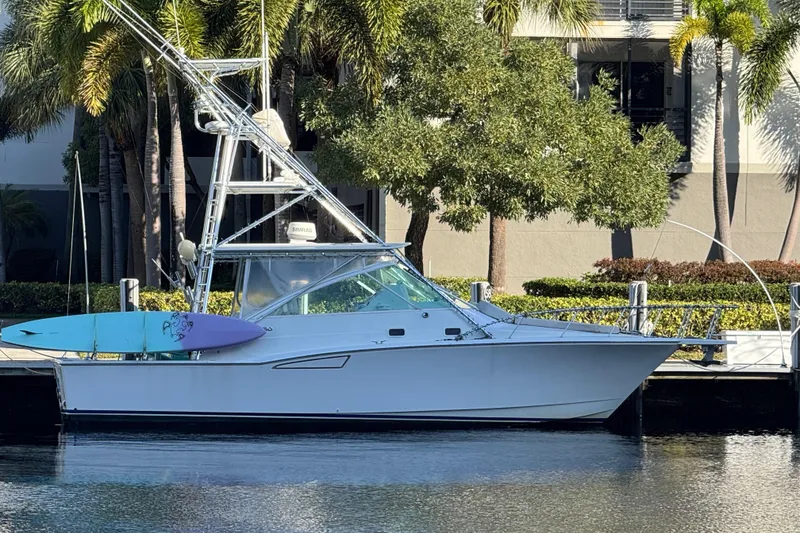Slide: The Image of 2001 Cabo 35 Express boat docked with surfboard, surrounded by palm trees. - 2