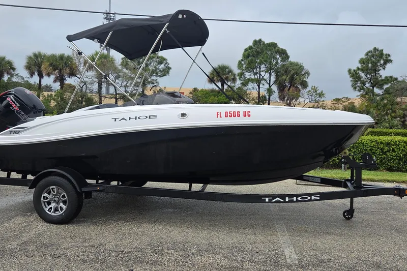 The Image of 2025 Tahoe T18 boat on trailer with canopy, parked outdoors. - 0