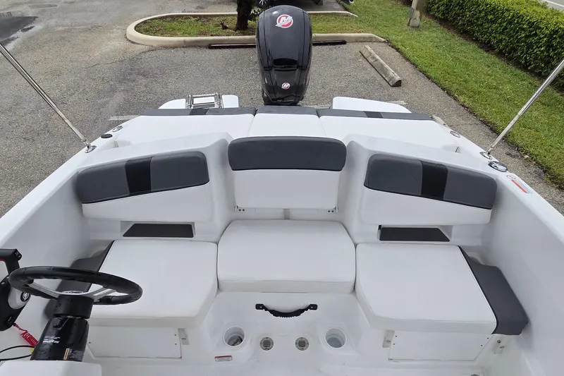 Slide: The Image of 2025 Tahoe T18 boat interior with cushioned seating and steering wheel, parked outdoors. - 12