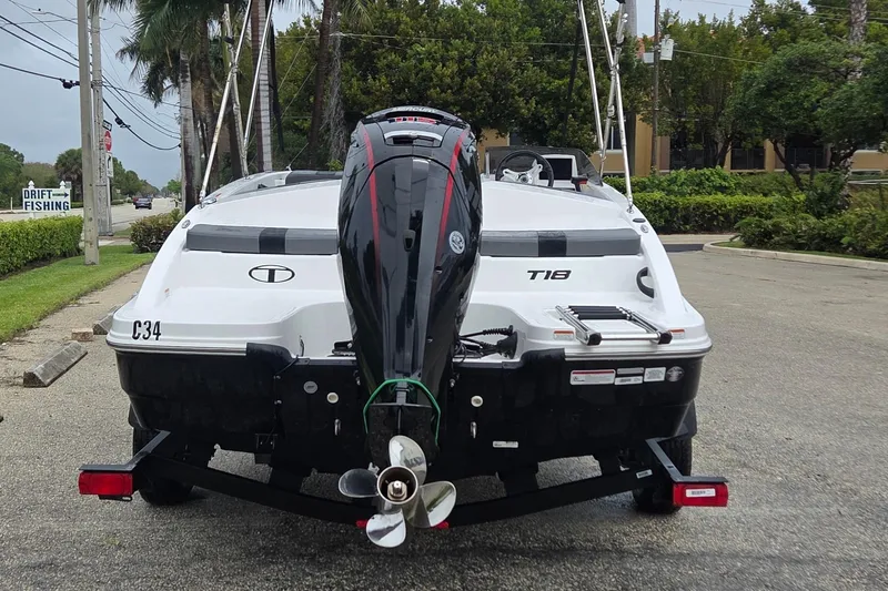 Slide: The Image of 2025 Tahoe T18 boat on trailer, rear view with outboard motor, parked roadside. - 2