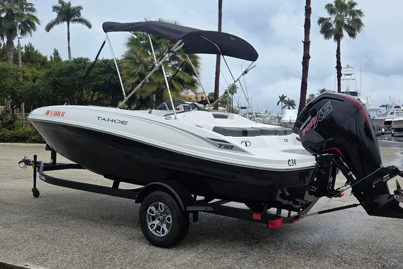 Slide: The Image of 2025 Tahoe T18 boat on trailer with outboard motor, parked near palm trees. - 3