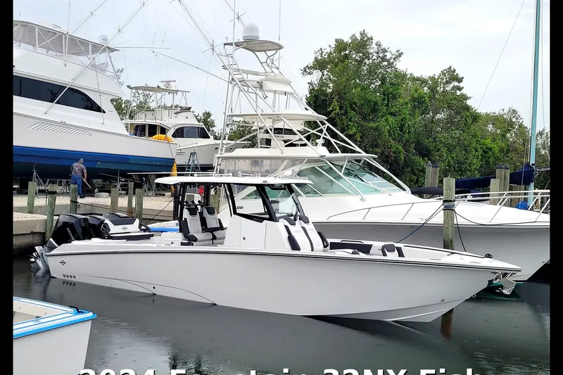 The Image of 2024 Fountain 32 NX Sportfish boat docked at marina, surrounded by other vessels. - 0