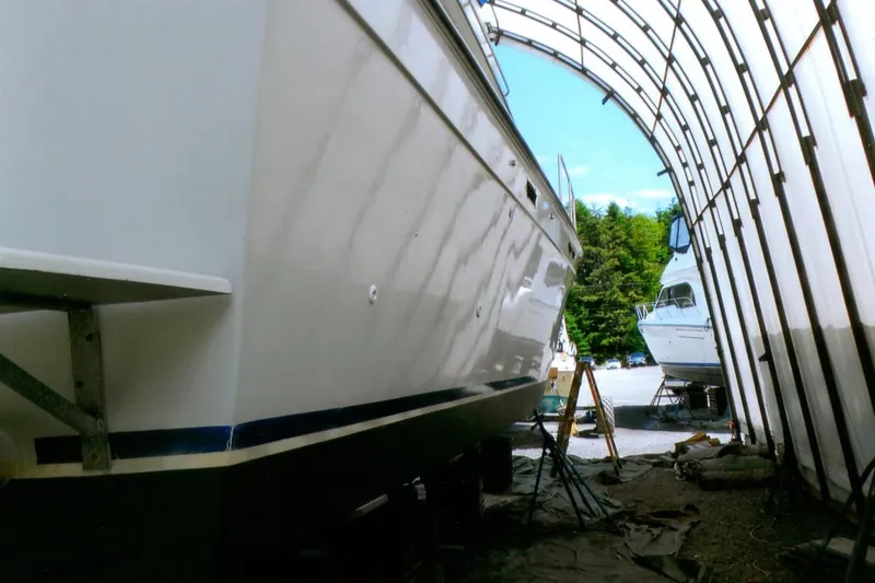 Slide: The Image of 1986 Custom Lynnwood Flybridge Sedan in storage, under a protective canopy. - 101