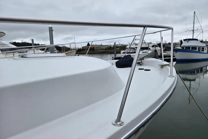 Slide: The Image of 1986 Lynnwood Flybridge Sedan boat docked in a marina on a cloudy day. - 13