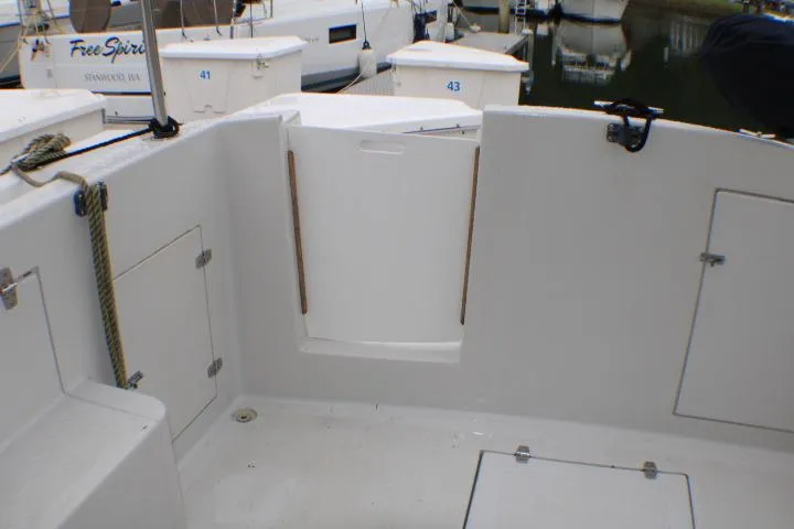 Slide: The Image of 1986 Lynnwood Flybridge Sedan boat deck with storage compartments and docked vessels in background. - 19