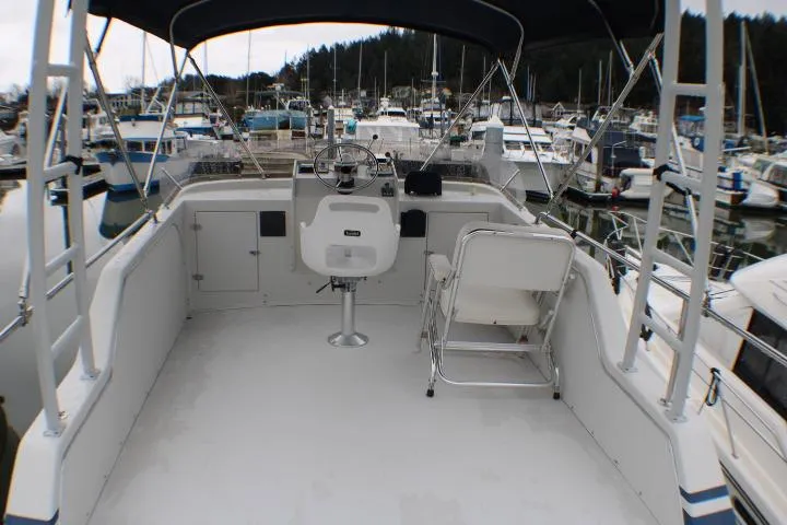 Slide: The Image of 1986 Lynnwood Flybridge Sedan boat with helm and seating, docked in a marina. - 29