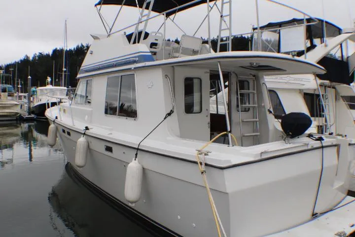 Slide: The Image of 1986 Lynnwood Flybridge Sedan docked at marina, featuring classic design and spacious deck. - 3