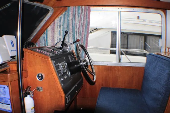 Slide: The Image of 1986 Lynnwood Flybridge Sedan helm with wooden dashboard and blue seating. - 42