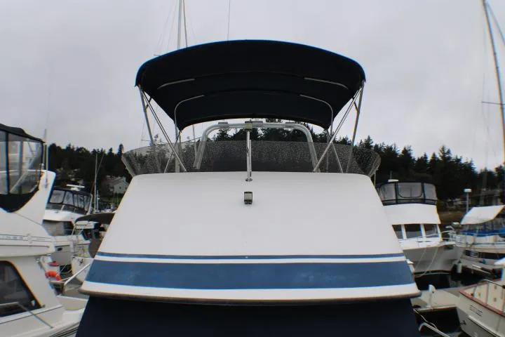 Slide: The Image of 1986 Lynnwood Flybridge Sedan boat docked at marina, featuring blue canopy and sleek design. - 5