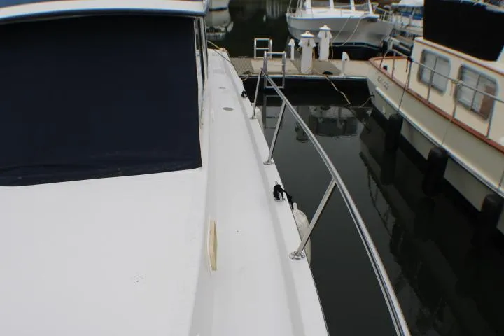 Slide: The Image of 1986 Lynnwood Flybridge Sedan docked, showcasing sleek deck and railing design. - 6