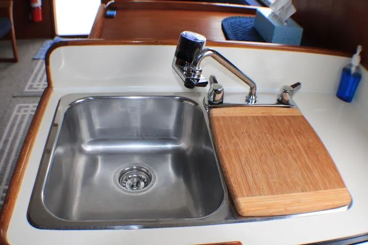 Slide: The Image of 1986 Lynnwood Flybridge Sedan kitchen sink with faucet and wooden cutting board. - 79
