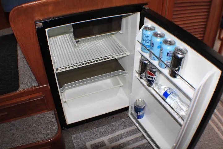 Slide: The Image of Open mini fridge on 1986 Lynnwood Flybridge Sedan, stocked with drinks and water bottles. - 84