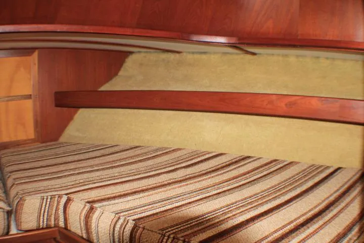 Slide: The Image of 1986 Lynnwood Flybridge Sedan cabin interior with striped bedding and wooden accents. - 90