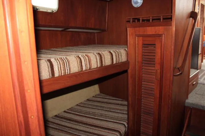 Slide: The Image of 1986 Lynnwood Flybridge Sedan interior with wooden bunk beds and striped cushions. - 92