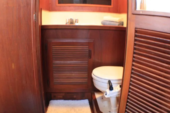 Slide: The Image of 1986 Lynnwood Flybridge Sedan bathroom with wooden cabinetry and compact toilet. - 95