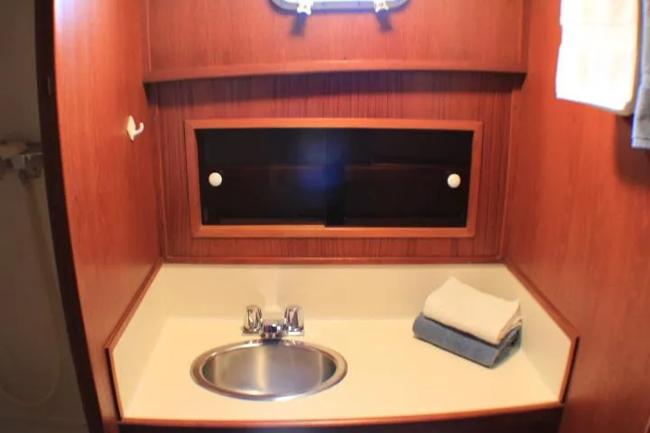 Slide: The Image of 1986 Lynnwood Flybridge Sedan bathroom with sink, wooden cabinetry, and folded towels. - 96