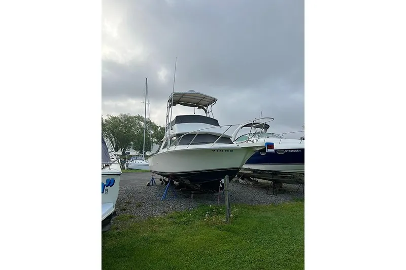 Slide: The Image of 1973 Bertram 28 Flybridge Cruiser on land, overcast sky, marina background. - 16
