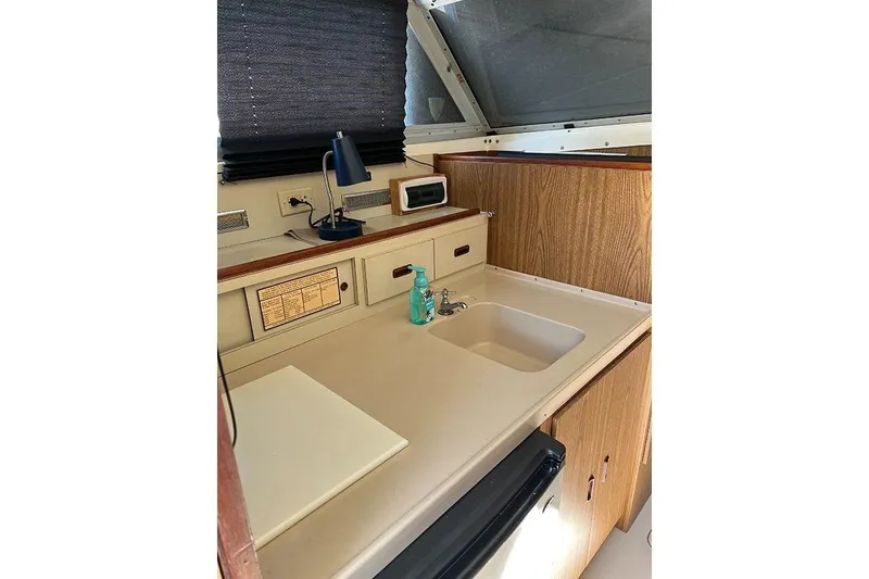 Slide: The Image of 1973 Bertram 28 Flybridge Cruiser interior with sink, countertop, and storage cabinets. - 5
