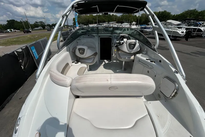 Slide: The Image of 2012 Crownline 236 SC boat interior with seating and steering wheel, parked outdoors. - 13