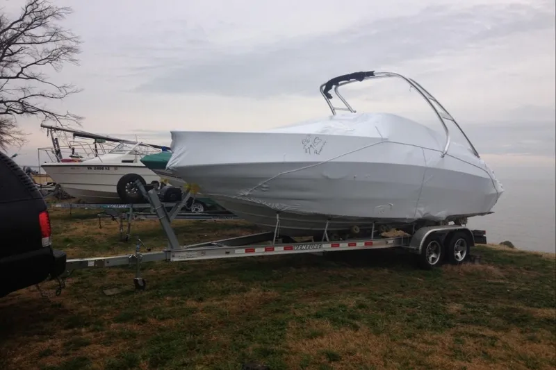 Slide: The Image of 2012 Crownline 236 SC boat covered on trailer near water. - 5