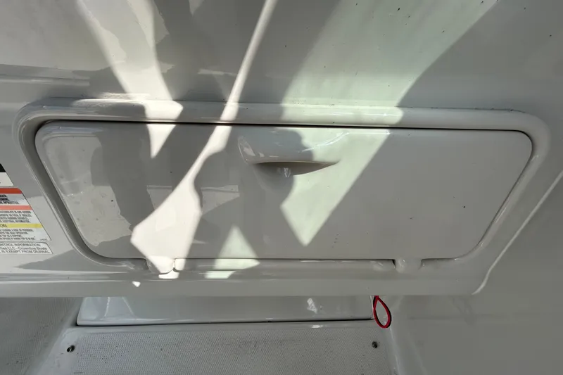 Slide: The Image of 2012 Crownline 236 SC boat storage compartment with handle and safety labels. - 55