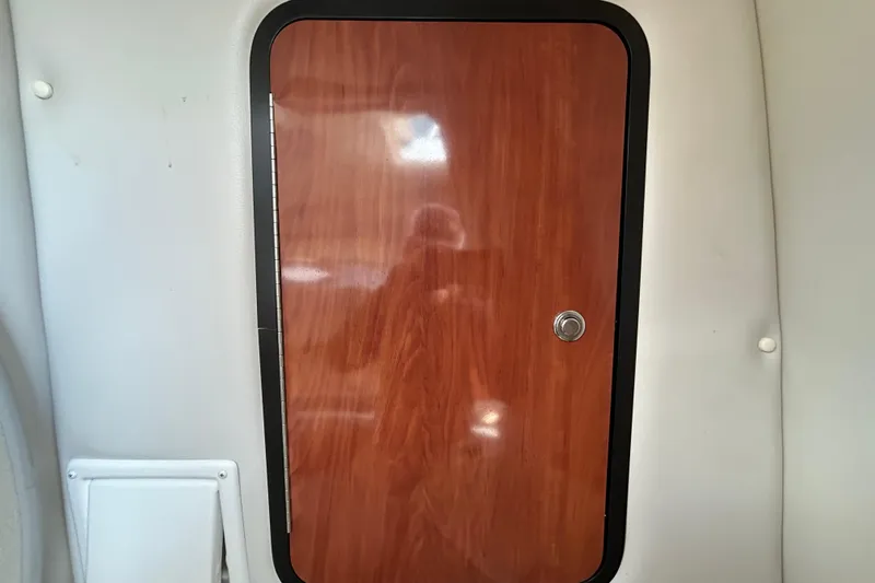 Slide: The Image of Wooden cabin door inside 2012 Crownline 236 SC boat, featuring sleek design and metallic handle. - 74