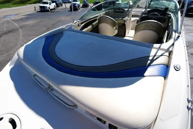 Slide: The Image of 2004 Sea Ray 200 Select boat interior with beige and blue seating, parked outdoors. - 8