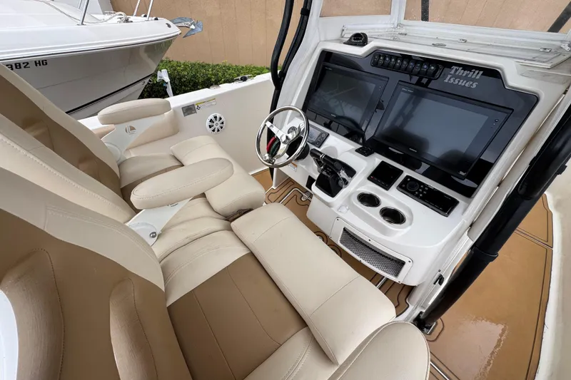 Slide: The Image of 2015 Sailfish 320 CC boat cockpit with dual screens and beige seating. - 12