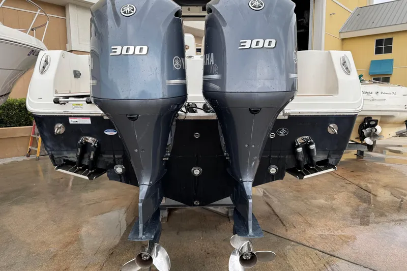 Slide: The Image of Twin Yamaha 300 engines on a 2015 Sailfish 320 CC boat, docked on wet pavement. - 2