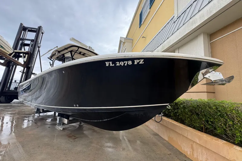 Slide: The Image of 2015 Sailfish 320 CC boat on display, black hull, docked near a building. - 3