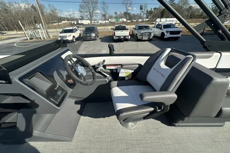 Slide: The Image of 2024 Manitou Cruise 22 Bench Tritoon interior with steering wheel and captain's chair. - 9