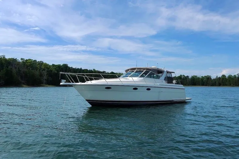 The Image of 1995 Tiara Yachts 3500 Express on serene water with forested shoreline. - 0