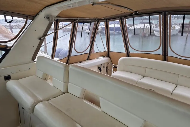 Slide: The Image of Interior of a 1995 Tiara Yachts 3500 Express with white seating and marina view. - 15
