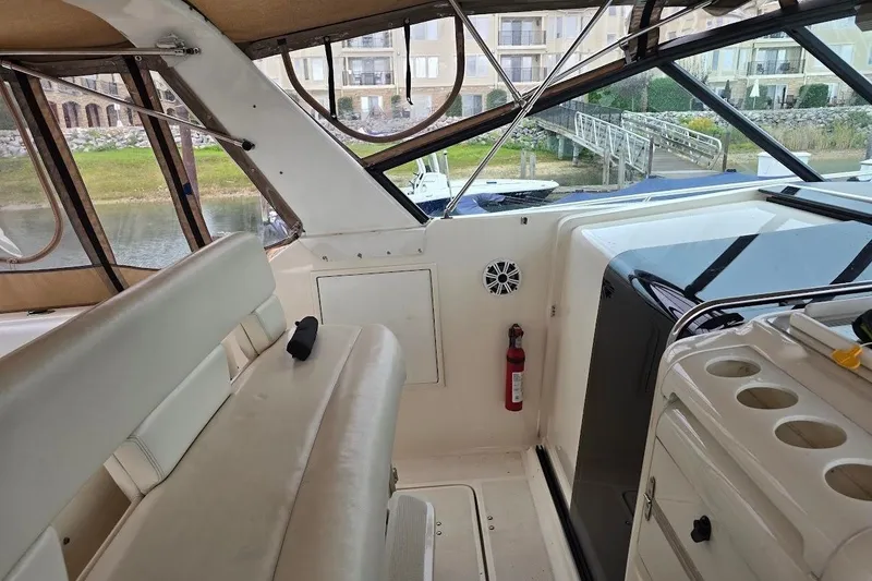 Slide: The Image of 1995 Tiara Yachts 3500 Express interior with seating, fire extinguisher, and waterfront view. - 18