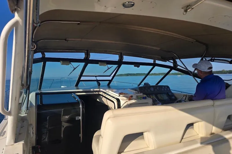 Slide: The Image of 1995 Tiara Yachts 3500 Express interior with captain navigating on calm waters. - 6