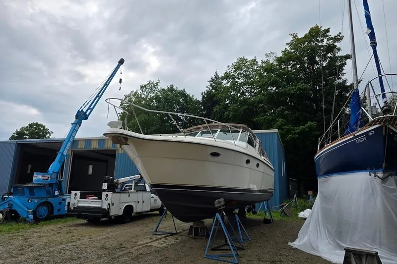 Slide: The Image of 1995 Tiara Yachts 3500 Express on stands near a blue crane and other boats. - 7