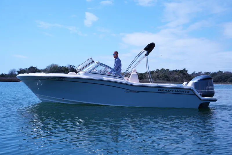 Slide: The Image of 2019 Grady-White Freedom 215 boat on calm water under clear blue sky. - 12