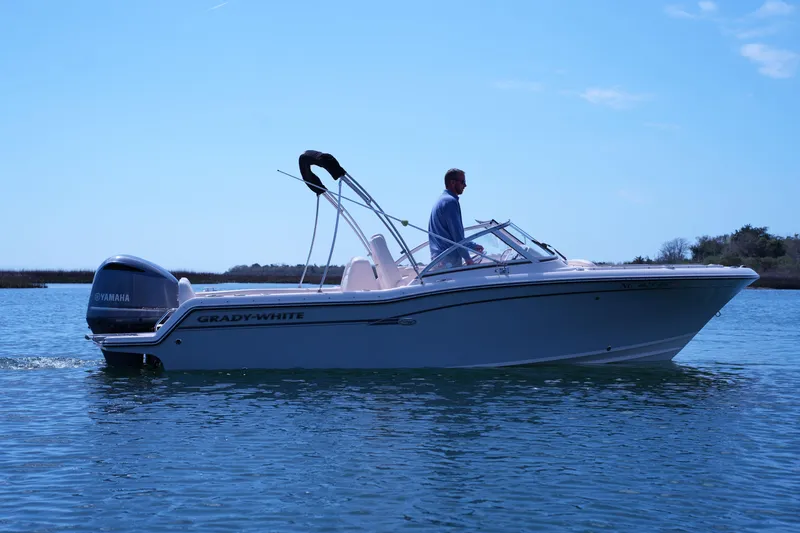Slide: The Image of 2019 Grady-White Freedom 215 boat cruising on calm water under clear blue sky. - 2