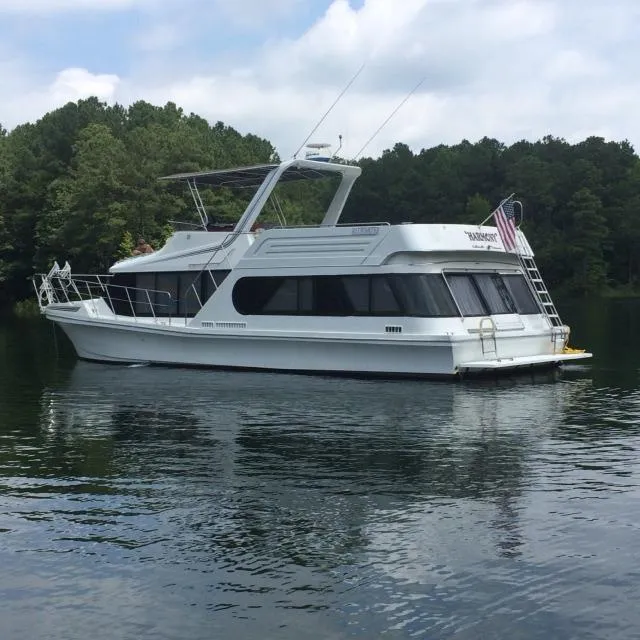 The Image of 1990 Bluewater Sedan boat on a calm lake with forested background. - 0