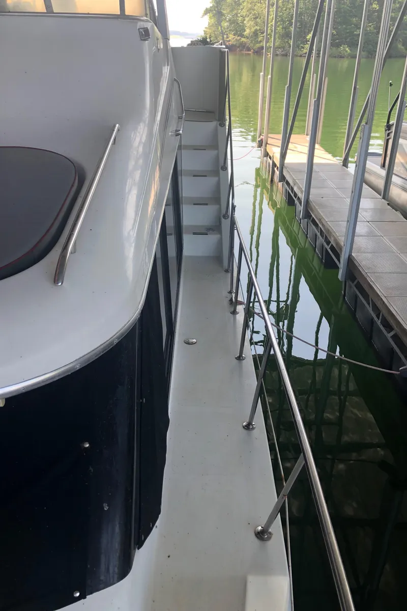 Slide: The Image of 1990 Bluewater Sedan boat docked, side view with railing and steps. - 10