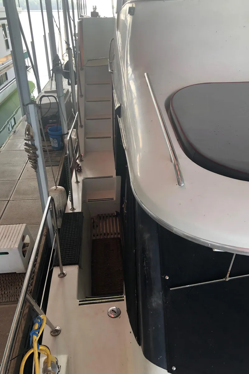 Slide: The Image of 1990 Bluewater Sedan boat docked at marina, side view of deck and stairs. - 11