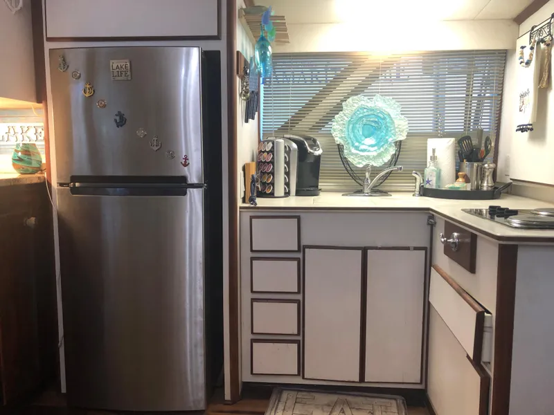 Slide: The Image of 1990 Bluewater Sedan kitchen with stainless steel fridge, white cabinets, and decorative accents. - 21
